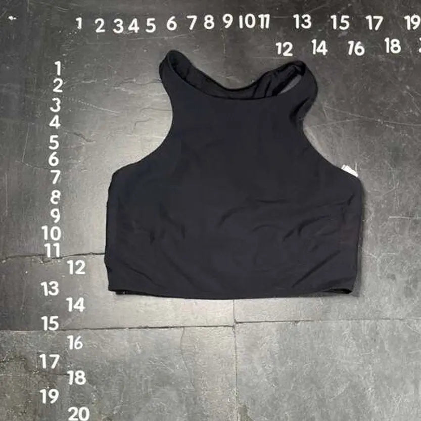 Black tank top on a gray floor with measurement markings