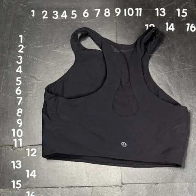 Black sports bra on a gray floor with measurement markings