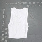 White tank top on a gray textured background with measurement scale