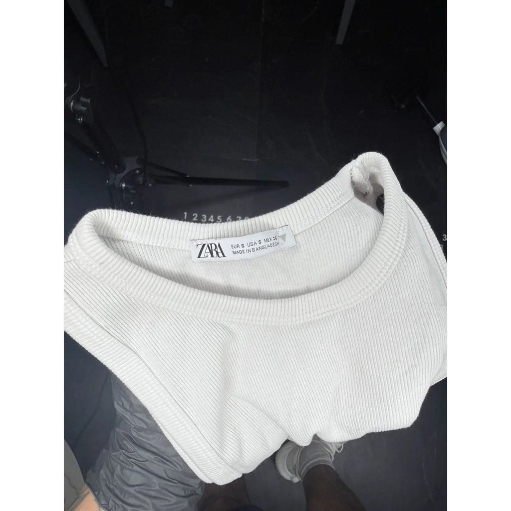 White knit beanie with a brand label on a dark background