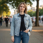 The Room Collective light wash denim trucker jacket on a woman wearing a black t-shirt and blue jeans. Features button front, chest pockets, and classic collar.