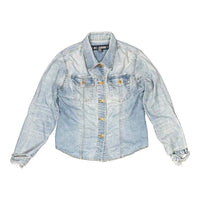 The Room Collective light wash denim trucker jacket with distressed cuffs and hem, featuring dual chest pockets and gold-tone buttons.